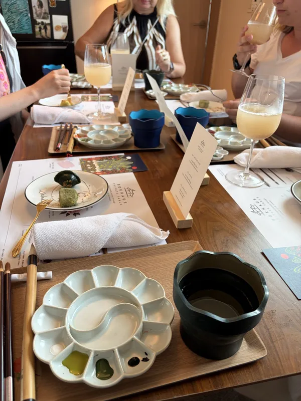 A palette and brushes laid out beside a printed menu card